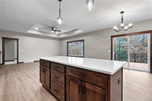 kitchen featuring light wood-type flooring, visible vents, a tray ceiling, and light countertops