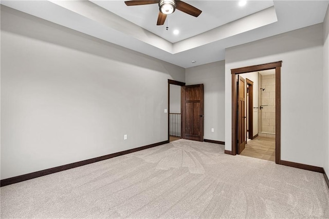 unfurnished bedroom with a tray ceiling, light carpet, baseboards, and recessed lighting