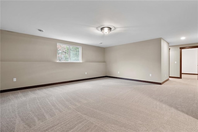 spare room featuring recessed lighting, light carpet, and baseboards