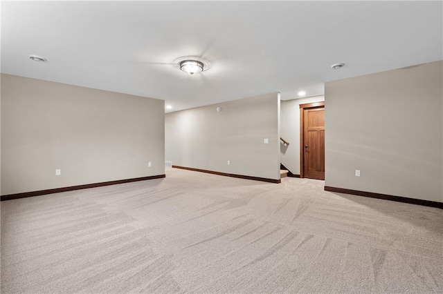 spare room with light carpet, stairway, and baseboards