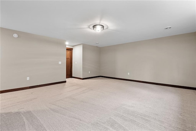 empty room featuring light colored carpet and baseboards