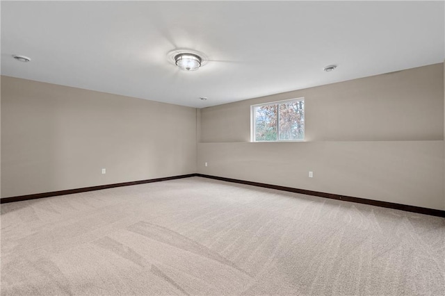 spare room featuring light carpet and baseboards