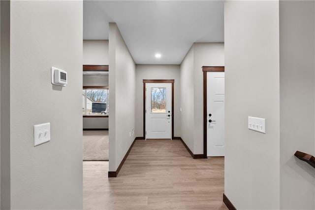 doorway to outside featuring baseboards and light wood-style floors