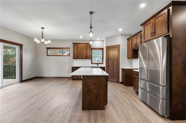 kitchen with freestanding refrigerator, backsplash, light countertops, and light wood-style flooring