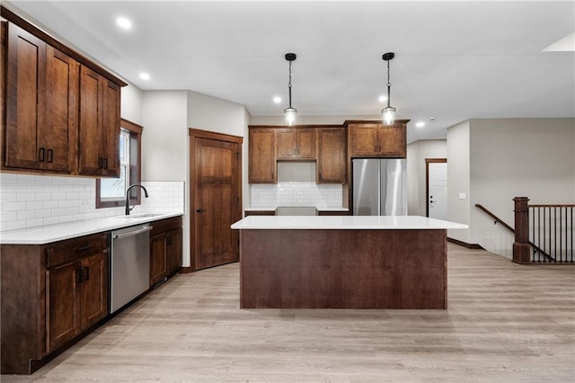 kitchen featuring light wood finished floors, light countertops, appliances with stainless steel finishes, and a center island