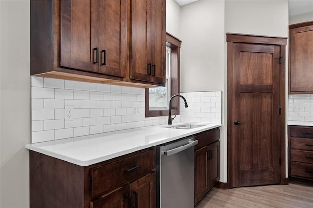 kitchen with dark brown cabinetry, light countertops, a sink, and stainless steel dishwasher