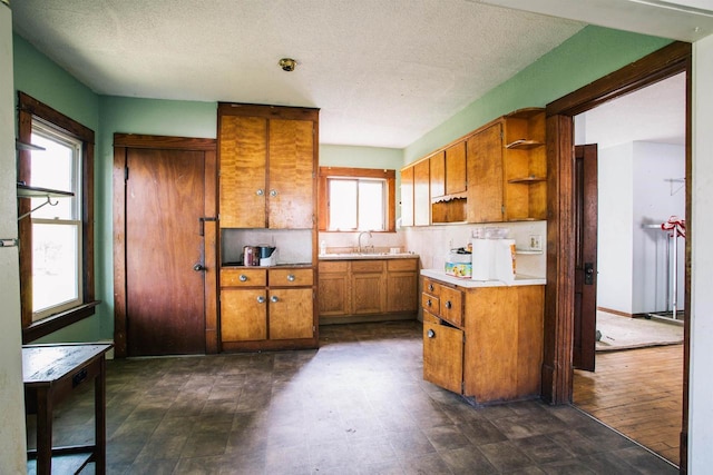 kitchen featuring a textured ceiling, a healthy amount of sunlight, and dark tile patterned flooring