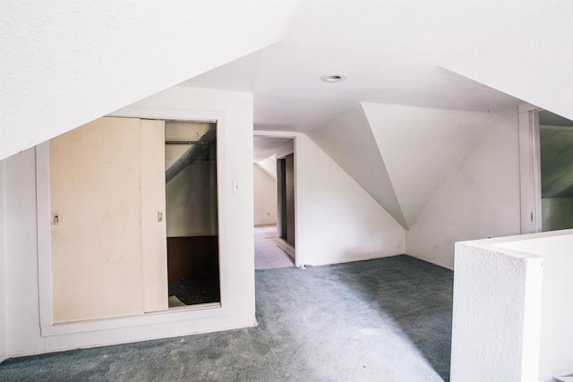 bonus room with dark carpet and vaulted ceiling