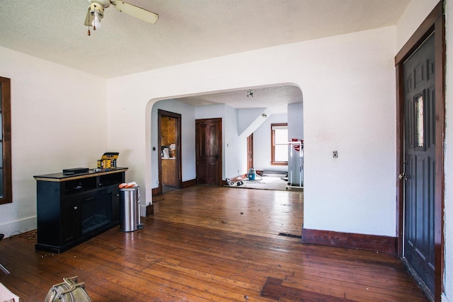 interior space with a textured ceiling, ceiling fan, and dark hardwood / wood-style floors