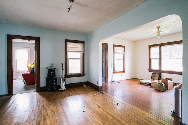 living room with a textured ceiling, ceiling fan, and hardwood / wood-style flooring