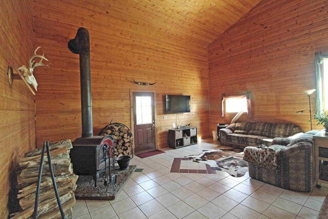 7750 Pine Rd, Arena, WI 53503 - tiled living area with high vaulted ceiling, wood walls, a wood stove, and wooden ceiling