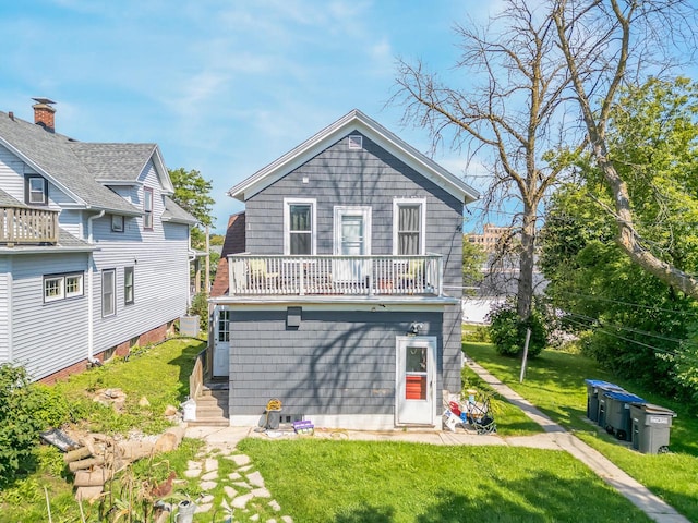 back of property featuring a balcony and a lawn