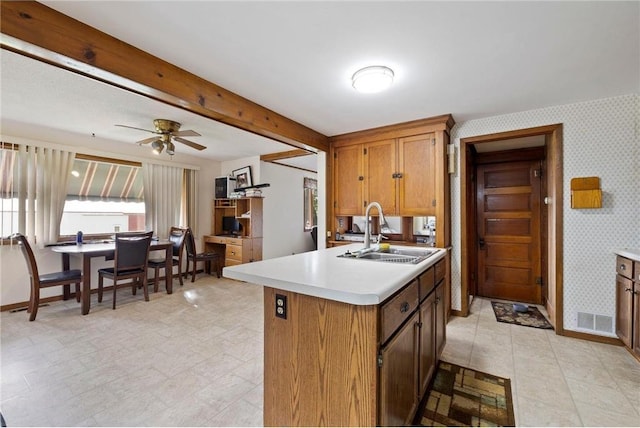 kitchen featuring light countertops, a sink, visible vents, and wallpapered walls