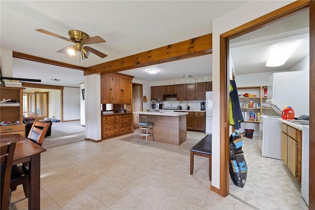 kitchen with a breakfast bar area, open floor plan, light countertops, light floors, and beam ceiling