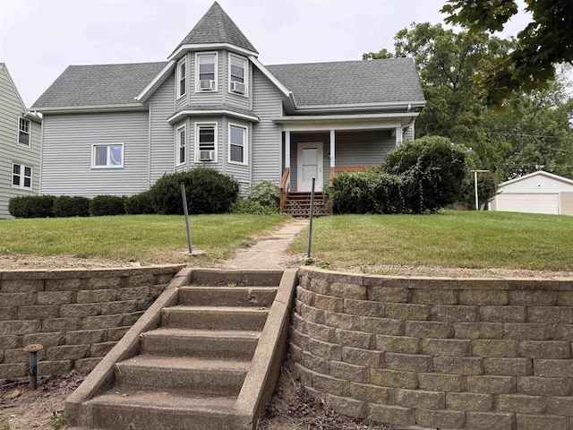 victorian-style house with a shingled roof, a detached garage, and a front lawn