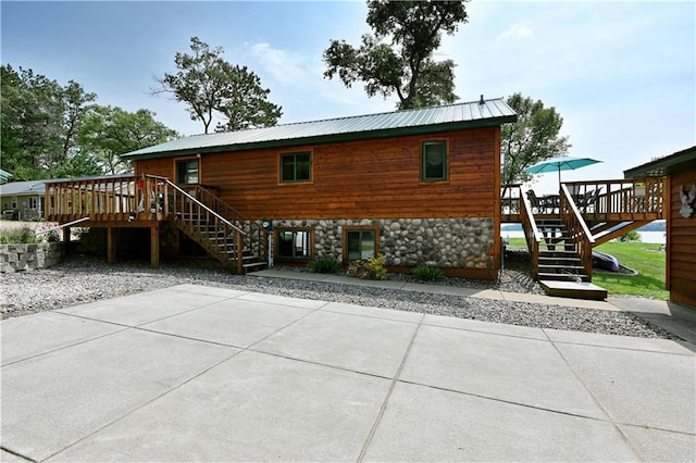 rear view of property featuring a wooden deck and a patio area