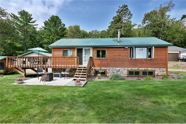 1175 Carson Rd, Spooner, WI 54801 - back of property with a fire pit, a lawn, a patio, metal roof, and a deck
