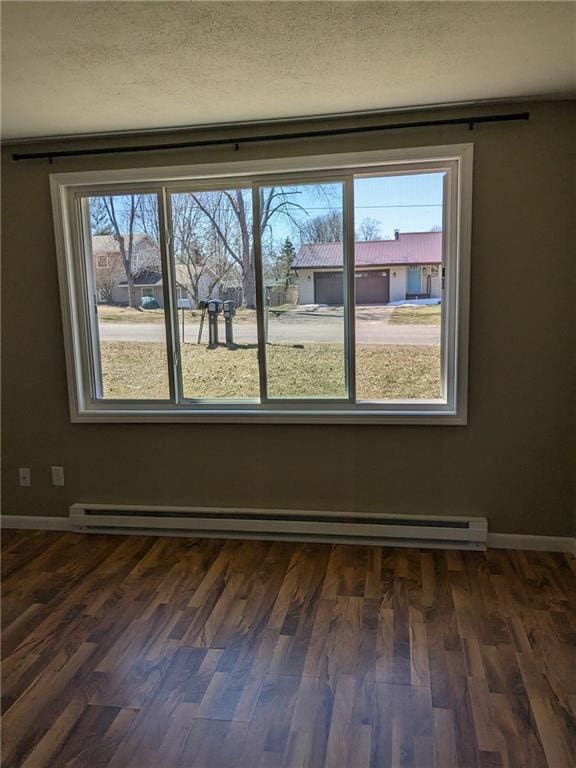 spare room featuring dark hardwood / wood-style flooring, a baseboard radiator, and a textured ceiling