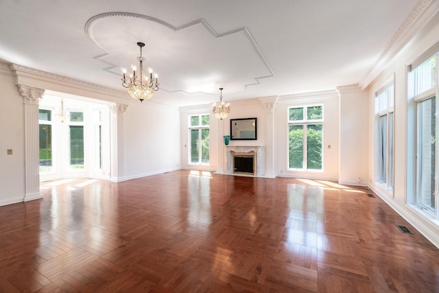 unfurnished living room with crown molding, plenty of natural light, a notable chandelier, and a premium fireplace