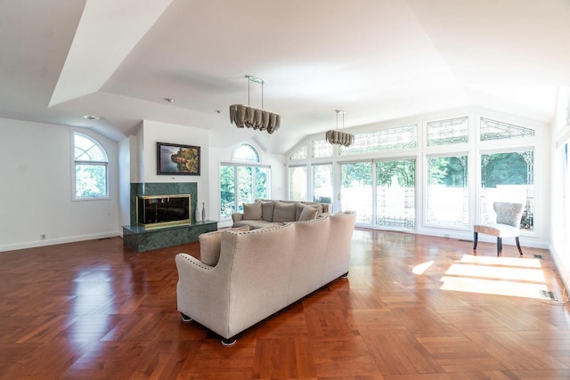 living area with lofted ceiling, visible vents, baseboards, and a high end fireplace