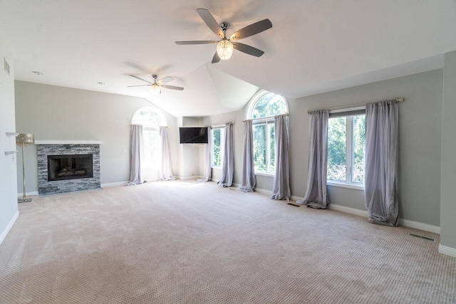 unfurnished living room with lofted ceiling, a stone fireplace, light colored carpet, visible vents, and baseboards