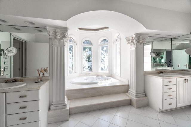 bathroom featuring a garden tub, two vanities, a sink, and ornate columns