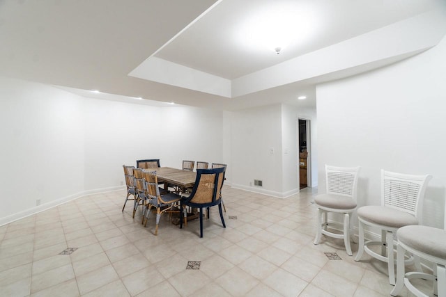 dining space with recessed lighting, a raised ceiling, and baseboards