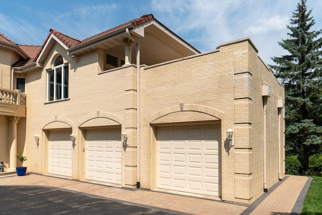 exterior space featuring brick siding, a tile roof, and a balcony