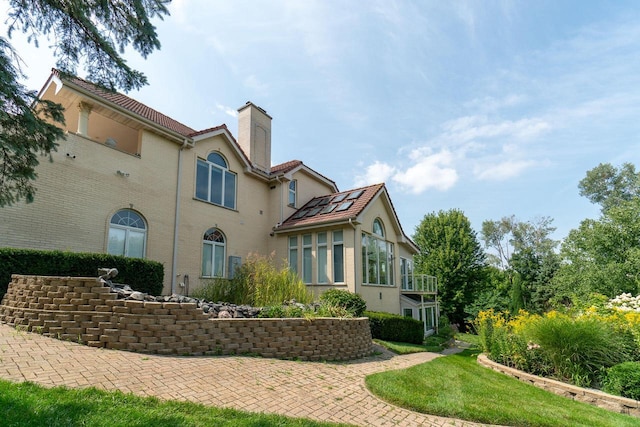 exterior space with a chimney, a balcony, and stucco siding