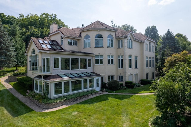 rear view of property with a sunroom, a chimney, and a lawn