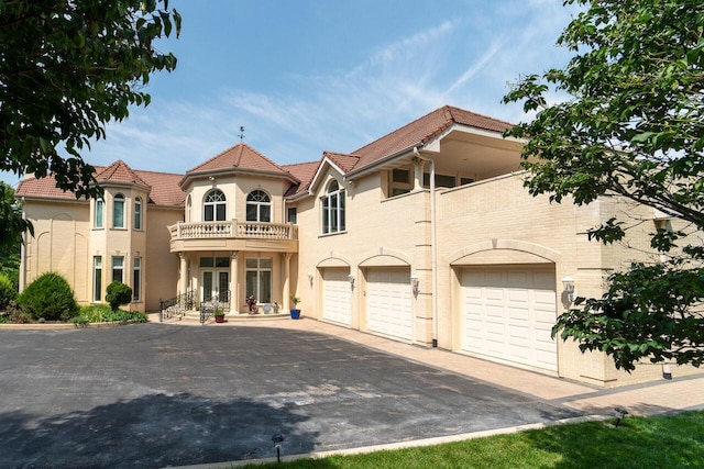 mediterranean / spanish-style home featuring driveway, a tile roof, and a balcony