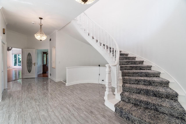 entrance foyer featuring a chandelier, ornamental molding, stairway, and baseboards