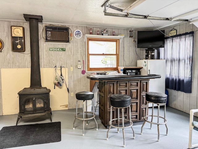 bar featuring a wood stove, dark brown cabinets, wood walls, and a wall mounted air conditioner