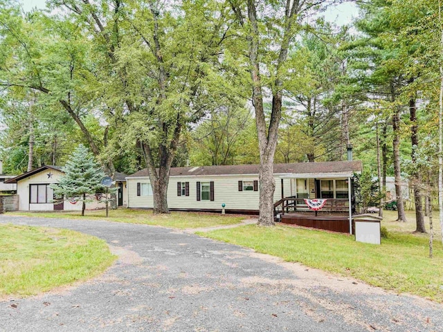 view of front of house with a porch, an outbuilding, gravel driveway, and a front lawn