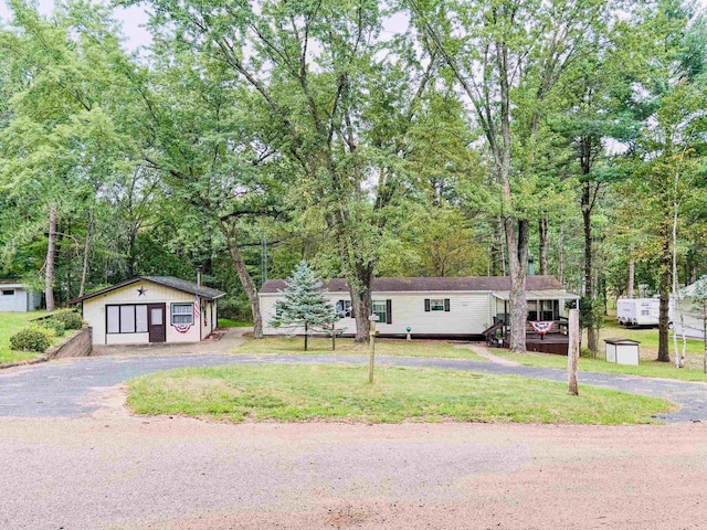 view of front of home featuring a garage, a front yard, and an outbuilding