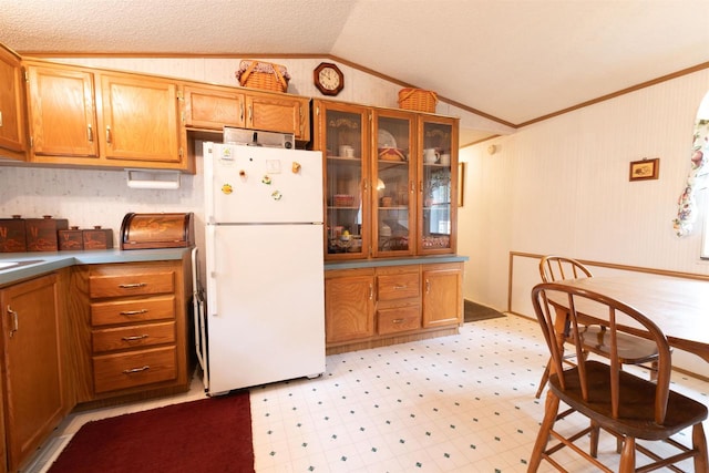 kitchen featuring ornamental molding, vaulted ceiling, white fridge, and light tile patterned floors