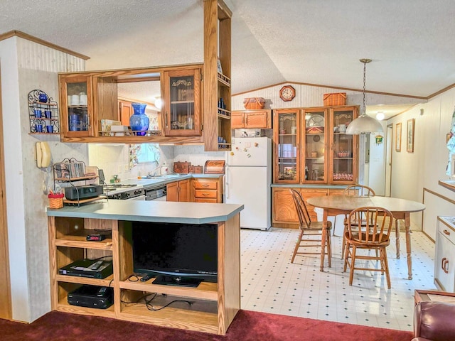 kitchen with lofted ceiling, freestanding refrigerator, brown cabinets, glass insert cabinets, and pendant lighting