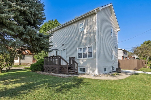 back of house with central AC unit and a yard