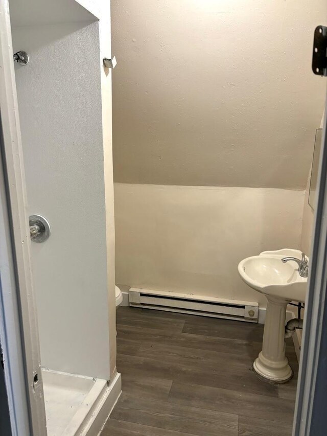 bathroom featuring wood-type flooring, toilet, and baseboard heating