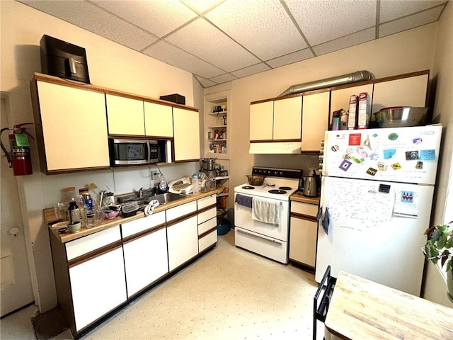 kitchen featuring cream cabinets, white appliances, and a drop ceiling