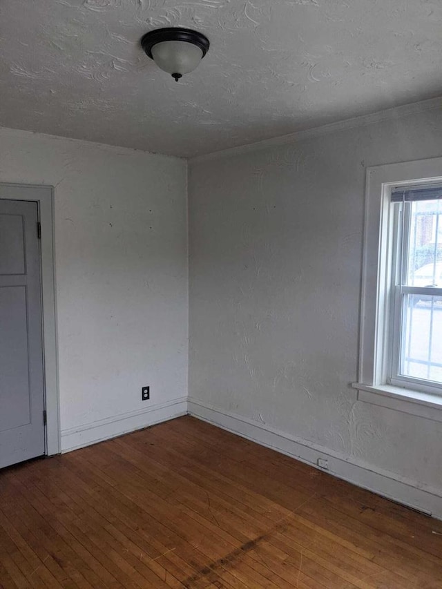 unfurnished room with baseboards, a textured ceiling, and hardwood / wood-style floors