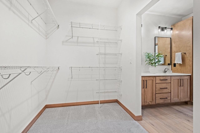 walk in closet featuring a sink and light wood-style flooring