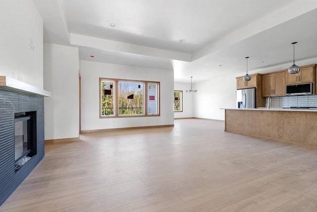 unfurnished living room with a notable chandelier, a fireplace, and light hardwood / wood-style floors