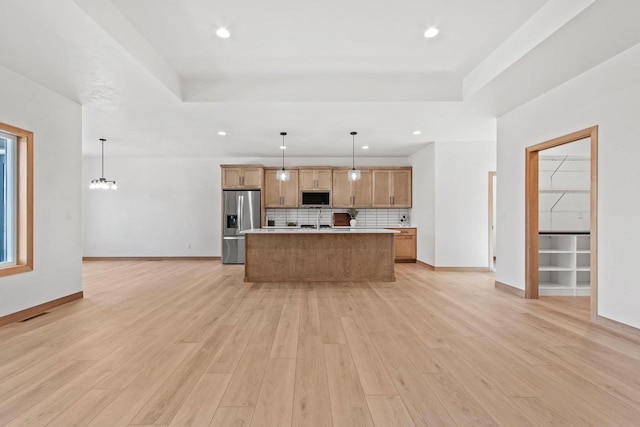 kitchen featuring light wood-style floors, stainless steel appliances, decorative backsplash, and a raised ceiling