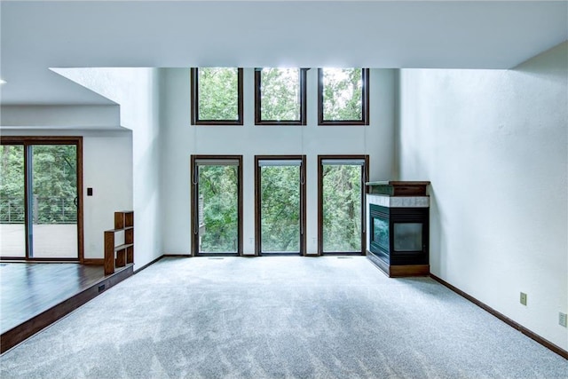 unfurnished living room featuring light colored carpet, a multi sided fireplace, and a healthy amount of sunlight