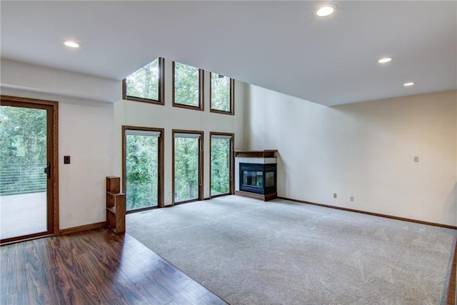 unfurnished living room featuring plenty of natural light, a multi sided fireplace, and wood-type flooring