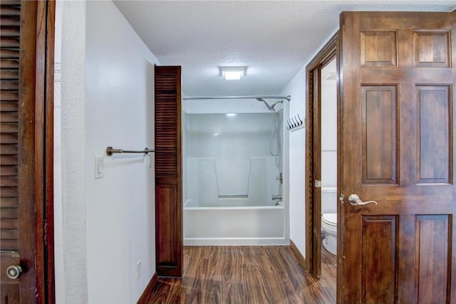 bathroom with shower / bathtub combination, hardwood / wood-style floors, toilet, and a textured ceiling