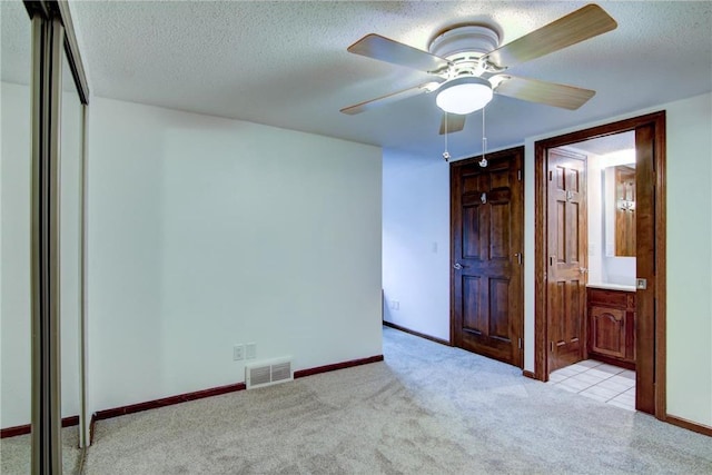 spare room with ceiling fan, light tile patterned flooring, and a textured ceiling