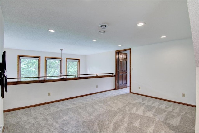 empty room with light colored carpet and a textured ceiling