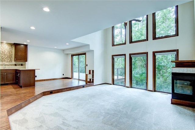 unfurnished living room with light wood-type flooring, a multi sided fireplace, and sink